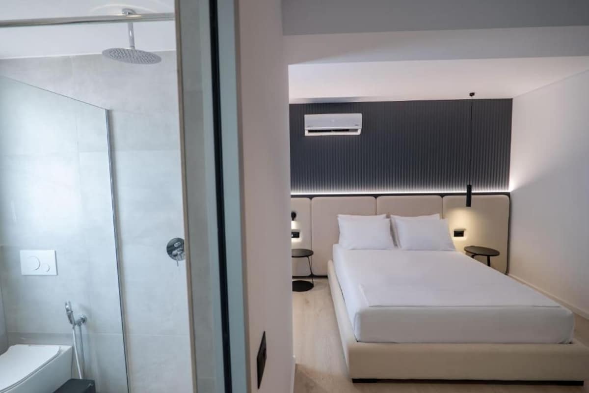 Una habitación de hotel moderna con ducha, cama y aire acondicionado de pared.