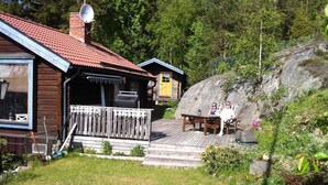 A wooden cabin with a red-tiled roof, a deck, and a barbecue area. - 4 Star Holiday Home in Musko (Muskö)