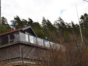 En tvåvåningsbyggnad med ett sluttande tak, omgiven av träd och annan växtlighet.
