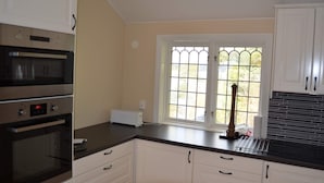A kitchen with white cabinets, a black countertop, and a window with a grid pattern. - 4 Star Holiday Home in Musko (Muskö)