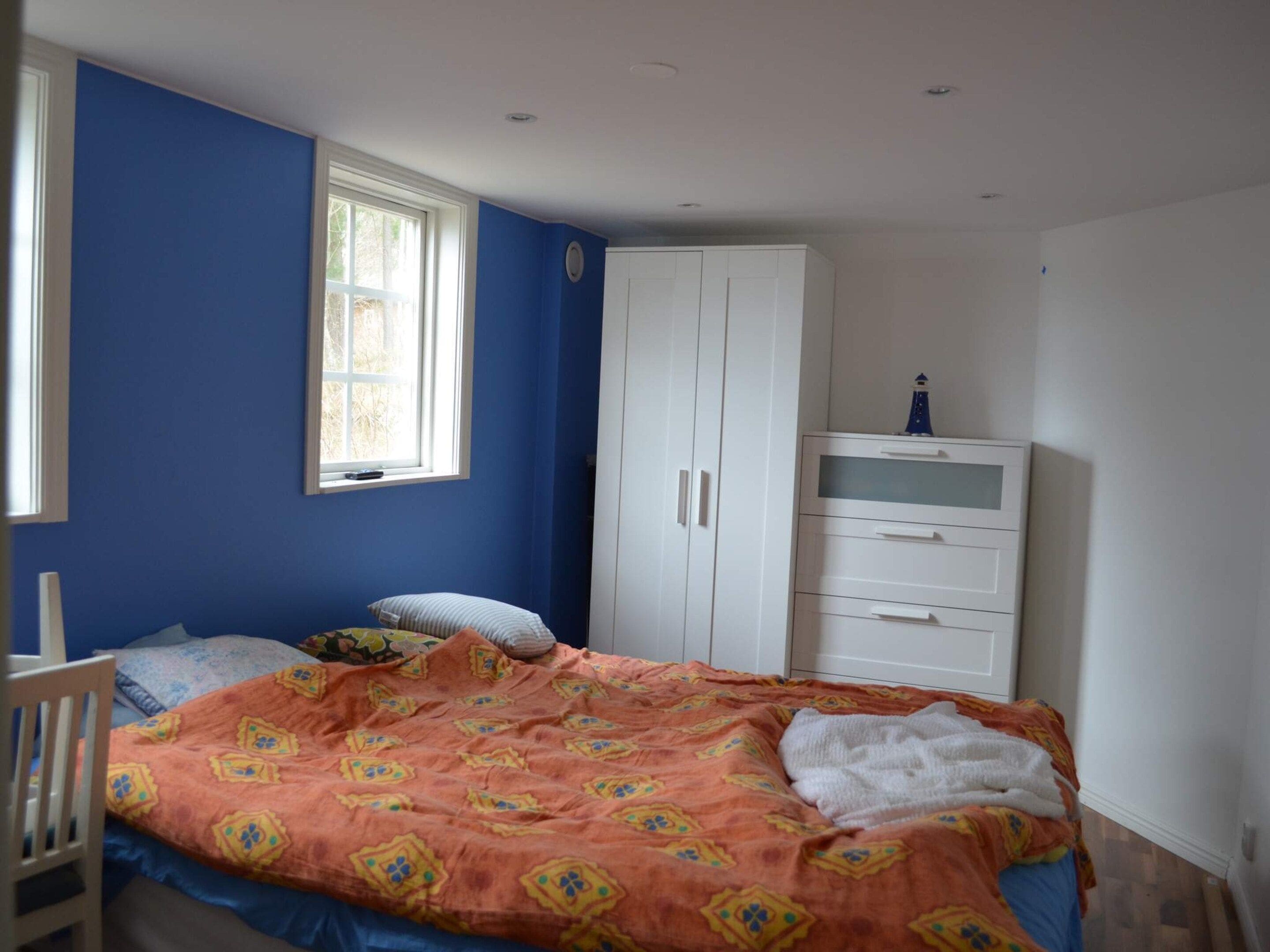 Ein Schlafzimmer mit einem Bett, einem Kleiderschrank, einem Fenster und einem Babybett.