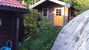 Une petite cabane en bois, avec un toit en pente, une porte en bois et une fenêtre.