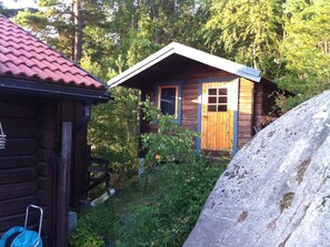 En liten stuga av trä med ett sluttande tak, en trädörr och ett fönster.