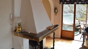 Une pièce dotée d’une cheminée, d’un plafond en bois et offrant une vue à travers une porte vitrée.