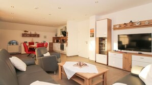 A modern living room with a sofa, a coffee table, and a TV. - Anchor Claw Comfortable Holiday Residence (Krummhoern)