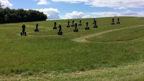 Um grupo de pessoas em segways em um campo gramado com céu claro.