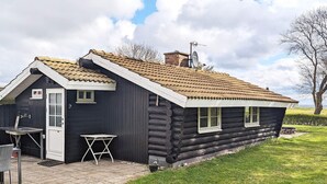 Uma cabana de tronco com telhado inclinado, um alpendre pequeno e uma antena parabólica.