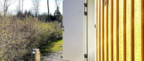 A wooden building with a white door, a metal container, and a wooden deck.