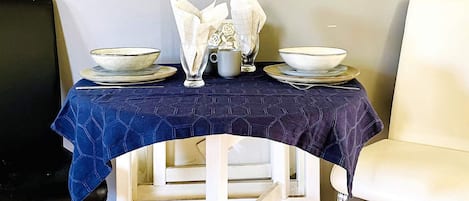 A dining table with plates, bowls, and a glass set.