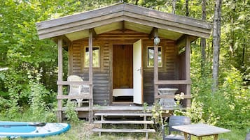 A wooden cabin with a porch, a bed, and a table.