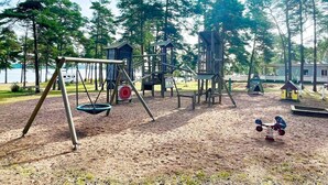 A playground with swings, climbing structures, and a small house. - 4 Star Holiday Home in Monsteras (Monsteras)