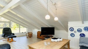 Un salon moderne avec une table en bois, un canapé en cuir noir et un téléviseur.