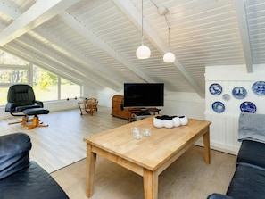 A modern living room with a wooden table, black leather sofa, and a television. - 4 Star Holiday Home in Albaek (Aalbaek)
