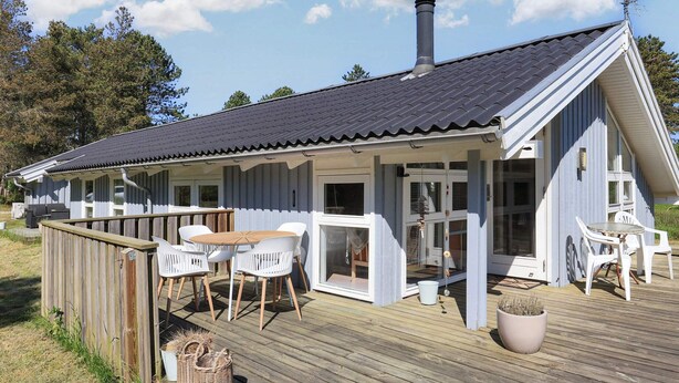 Une terrasse en bois avec des sièges extérieurs et un espace abrité.