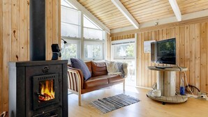Un salon chaleureux avec un poêle à bois, un canapé en cuir, une télévision et un décor intérieur en bois.