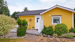 A yellow single-story house with a white door, a small porch, and a window with a plant. - 7 Person Holiday Home in Mellbystrand (Mellbystrand)