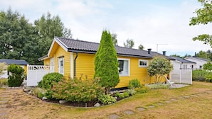 A yellow mobile home with a fenced yard, surrounded by trees and shrubs. - 7 Person Holiday Home in Mellbystrand (Mellbystrand)