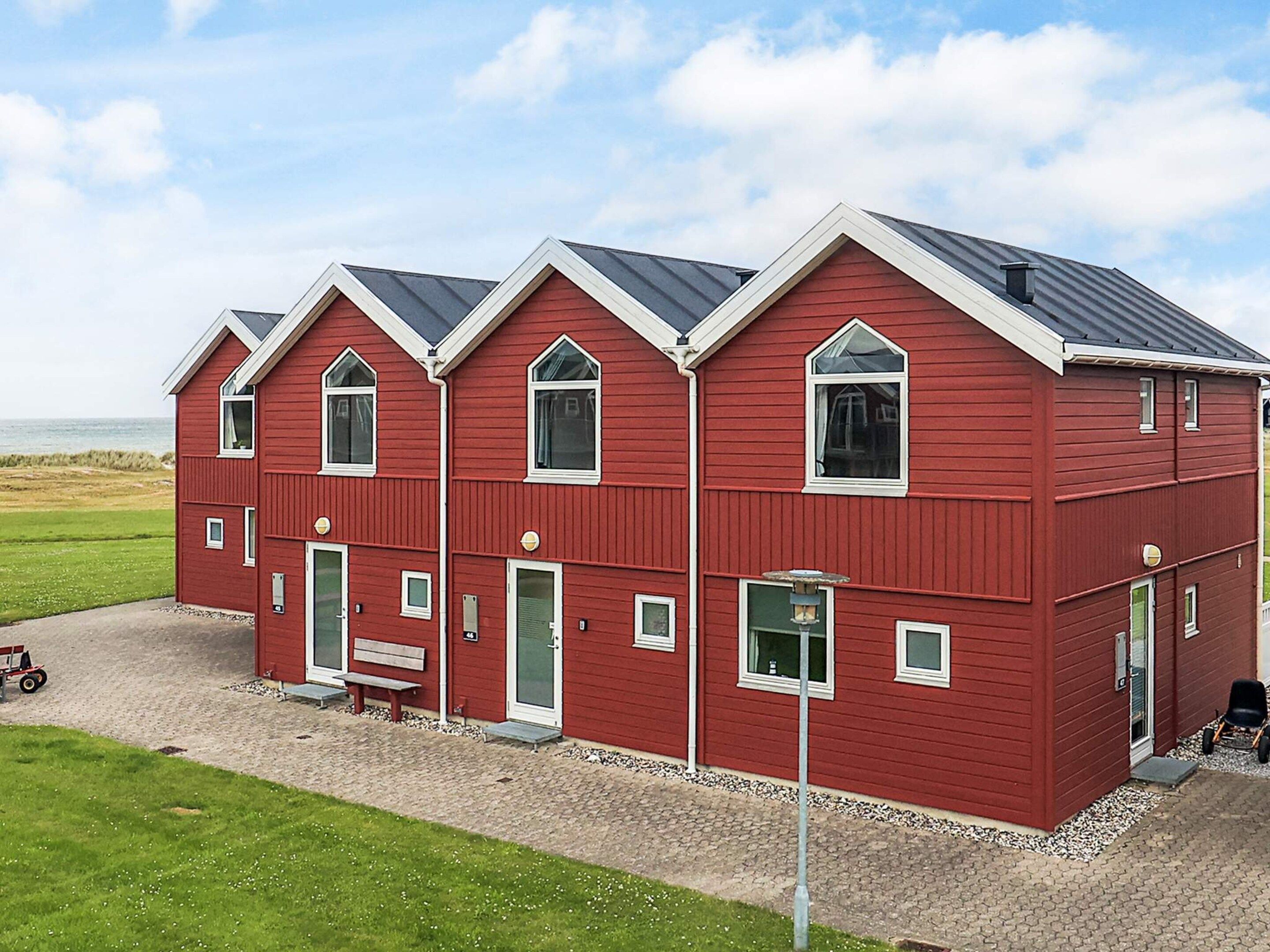 A red, multi-story building with a symmetrical facade, large windows, and a flat roof.
