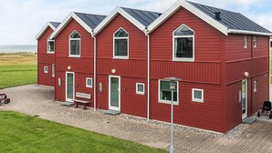 A red, multi-story building with a symmetrical facade, large windows, and a flat roof. - 6 Person Holiday Home in Hadsund (Hadsund)