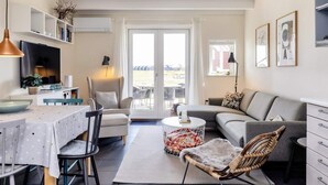 A modern living room with a dining area, a sofa, a chair, and a TV. - 6 Person Holiday Home in Hadsund (Hadsund)