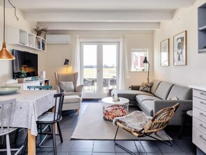 A modern living room with a dining area, a sofa, a chair, and a TV. - 6 Person Holiday Home in Hadsund (Hadsund)