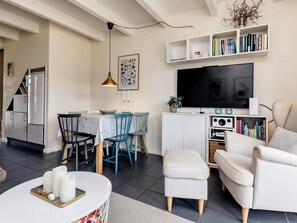 A modern living room with a flat-screen TV, a dining area with a table and chairs, and a kitchen with a refrigerator. - 6 Person Holiday Home in Hadsund (Hadsund)