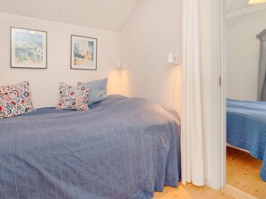 A bedroom with a bed, pillows, and two framed pictures on the wall. - 6 Person Holiday Home in Hadsund (Hadsund)