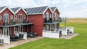 A red two-story building with a balcony and outdoor seating area. - 6 Person Holiday Home in Hadsund (Hadsund)