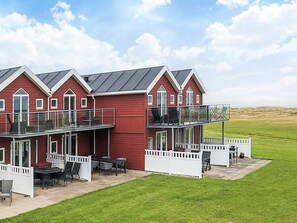 A red two-story building with a balcony and outdoor seating area. - 6 Person Holiday Home in Hadsund (Hadsund)