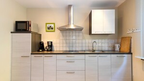 Une cuisine moderne avec des armoires blanches, une hotte de cuisinière en acier inoxydable, un four à micro-ondes et une machine à café.