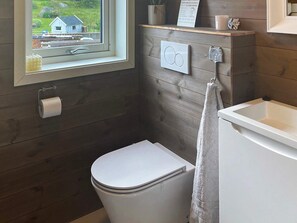 A small, compact bathroom with a toilet, a sink, and a window. - 8 Person Holiday Home in Tau (Strand)