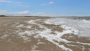 A beach with a wide sandy area, gentle waves, and a clear sky with clouds. - 5 Star Holiday Home in Romo (Rømø)