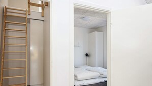 A room with a wooden ladder, a bed with white bedding, a grey bench, and a wardrobe. - 5 Star Holiday Home in Romo (Rømø)