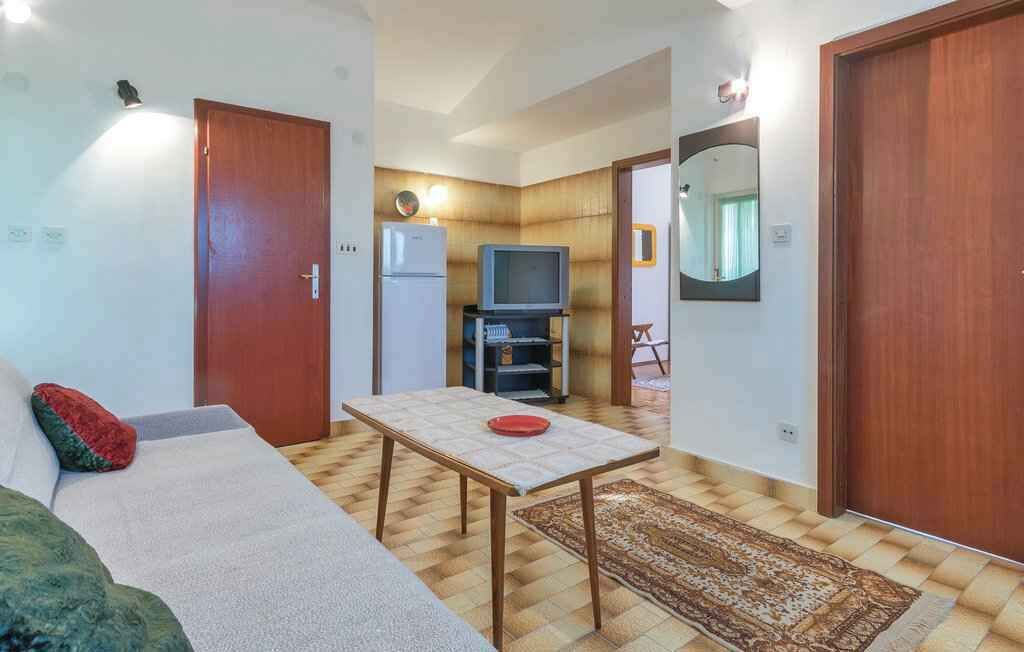 A compact living space with a sofa, a small table, a television, and a refrigerator.