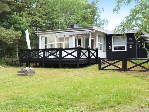 A house with a porch, a fenced yard, and a number '90' on the side. - 6 Person Holiday Home in Hadsund (Hadsund)