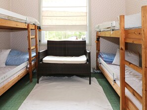 A room with two bunk beds, a wicker chair, and a window with blinds. - 6 Person Holiday Home in Hadsund (Hadsund)