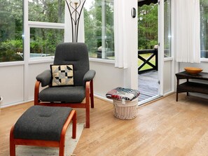 A cozy seating area with a chair and ottoman, a small table with a bowl, and a wicker basket. - 6 Person Holiday Home in Hadsund (Hadsund)