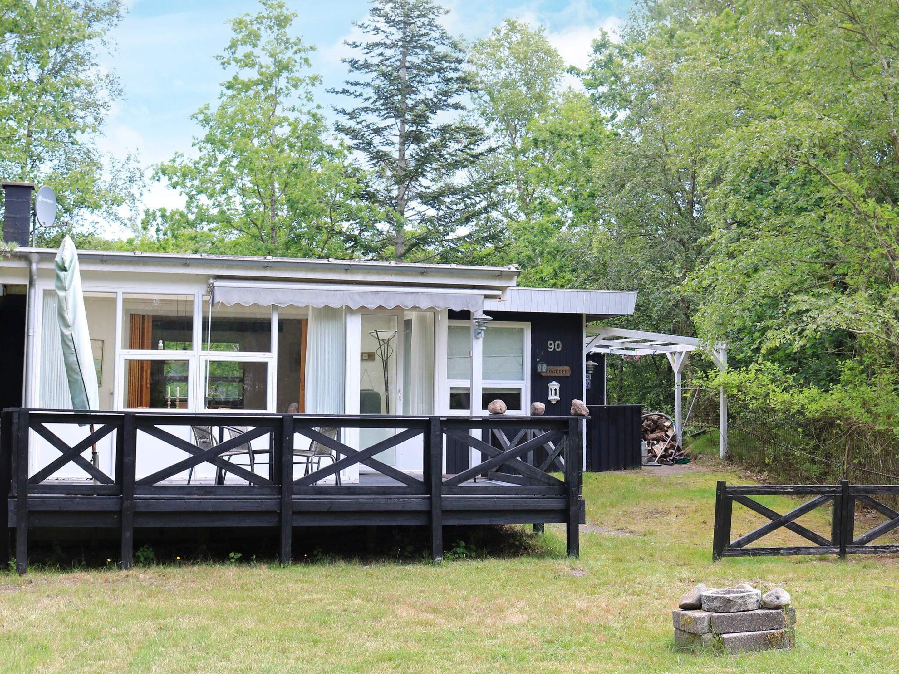 A cabin with a deck, a covered porch, and a number sign indicating its location.