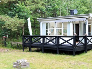 A small, single-story cabin with a deck, surrounded by trees. - 6 Person Holiday Home in Hadsund (Hadsund)