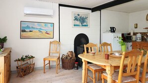 Un comedor con una mesa y sillas de madera, una chimenea y una cocina al fondo.
