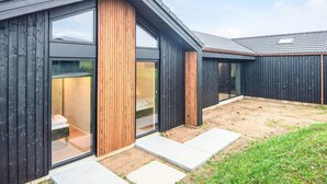 A modern building with large glass windows, wooden accents, and a sloped roof. - 5 Star Holiday Home in Borkop (Borkop)