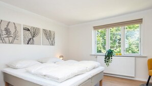 Una camera da letto con un letto, una finestra vista sul verde e opere d'arte alle pareti.