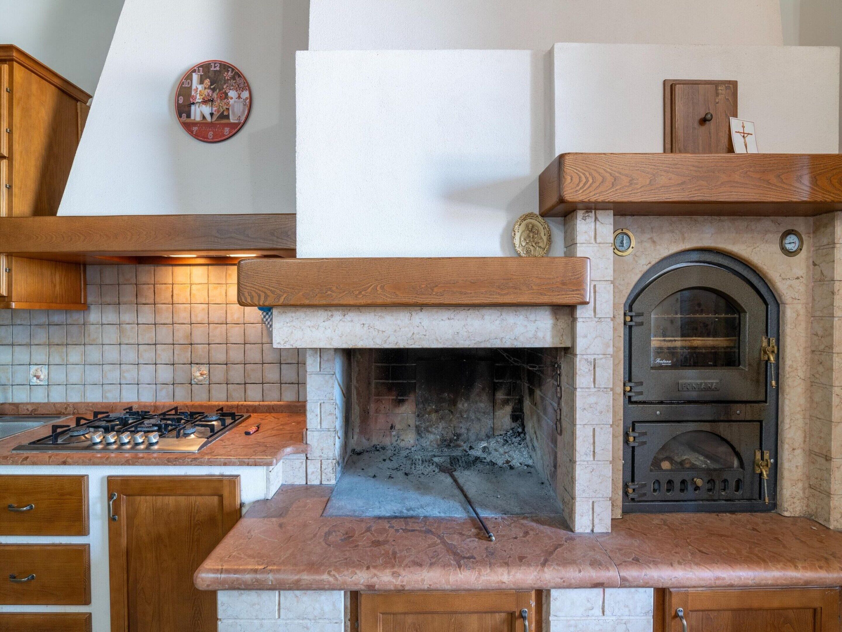 Una cocina con estufa a gas, estufa de leña y armarios de madera.
