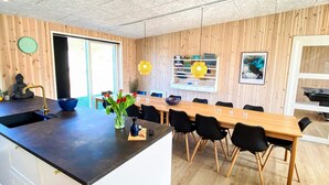 Een moderne keuken met een houten eiland, zwarte stoelen en een eettafel.