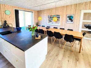 Una cocina moderna con una isla de madera, sillas negras y una mesa de comedor.