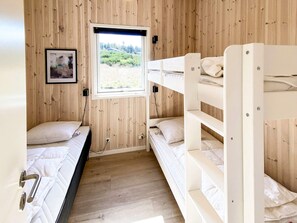 Habitación con literas, paredes de madera, una ventana y un cuadro en la pared.