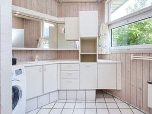 Modern kitchen with washing machine, large window, and wooden paneling.