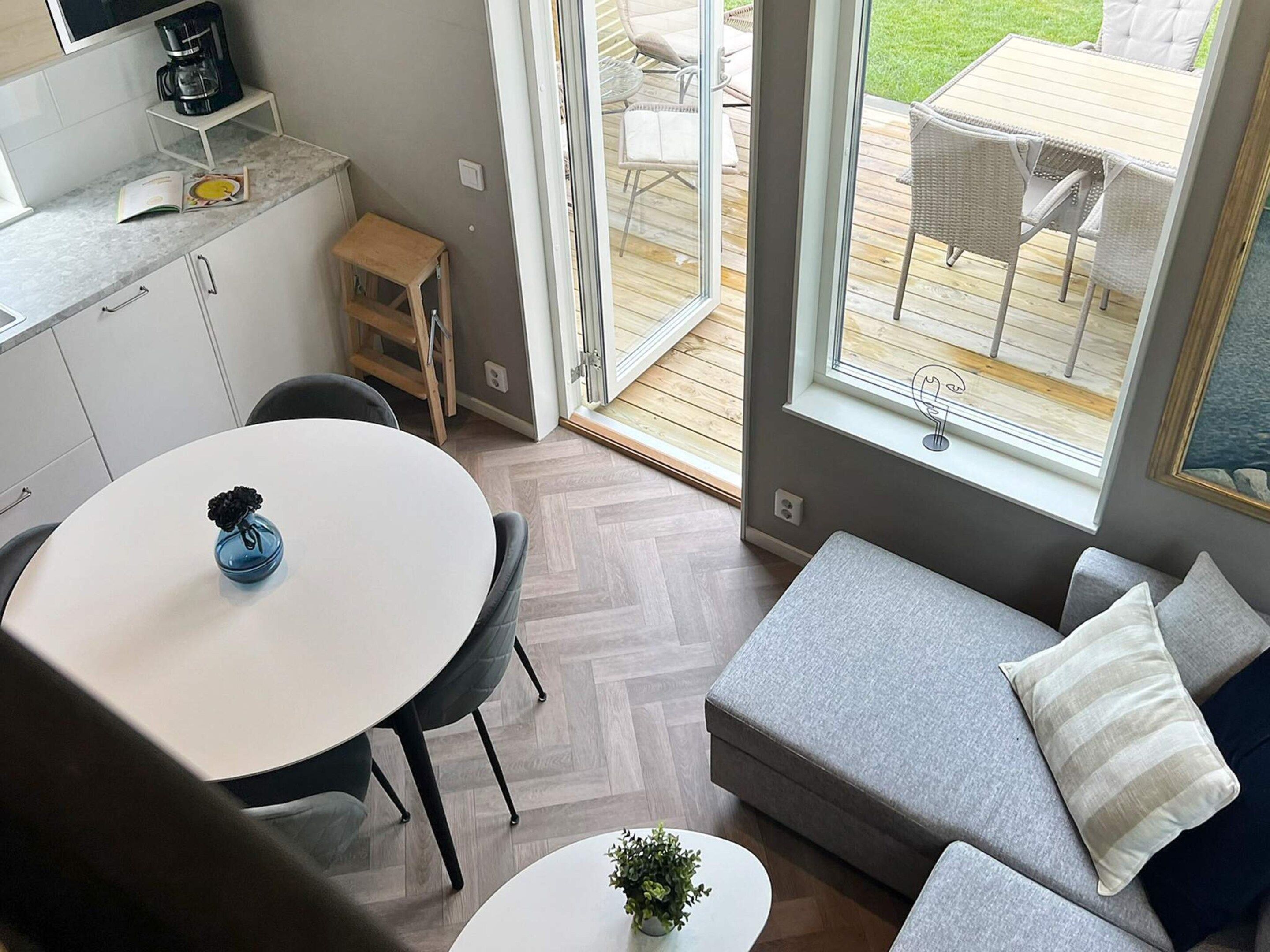 A modern kitchen with a dining area, a small table, and a sofa with cushions.