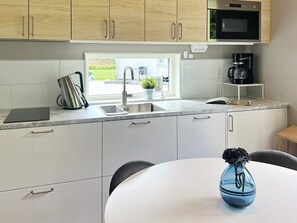 A modern kitchen with a built-in microwave, a sink, and a coffee maker.