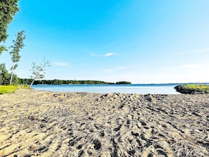 Una playa con una orilla arenosa y un cuerpo de agua tranquilo.